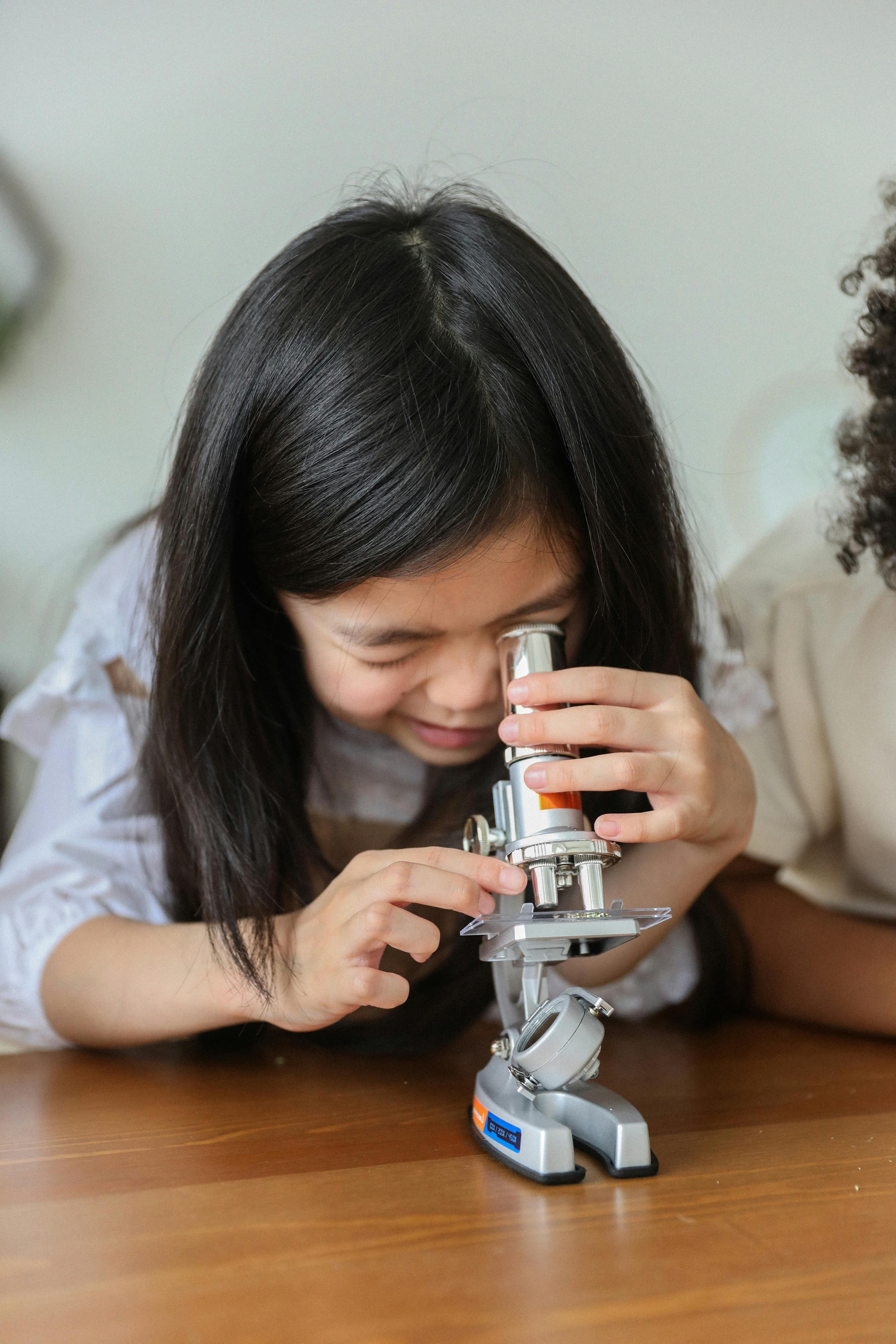 A young girl looking through a microscope.